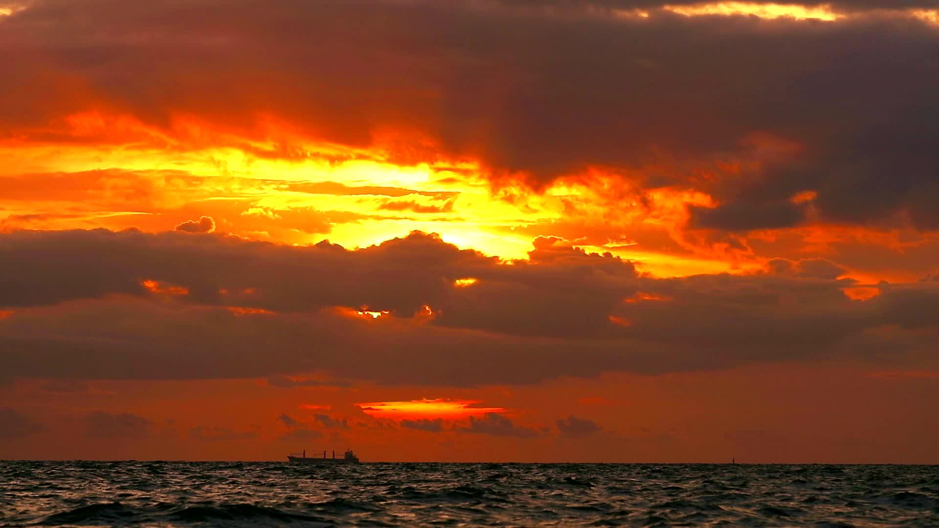 日落的橙色天空和深红的云彩在海面上飘动视频的预览图