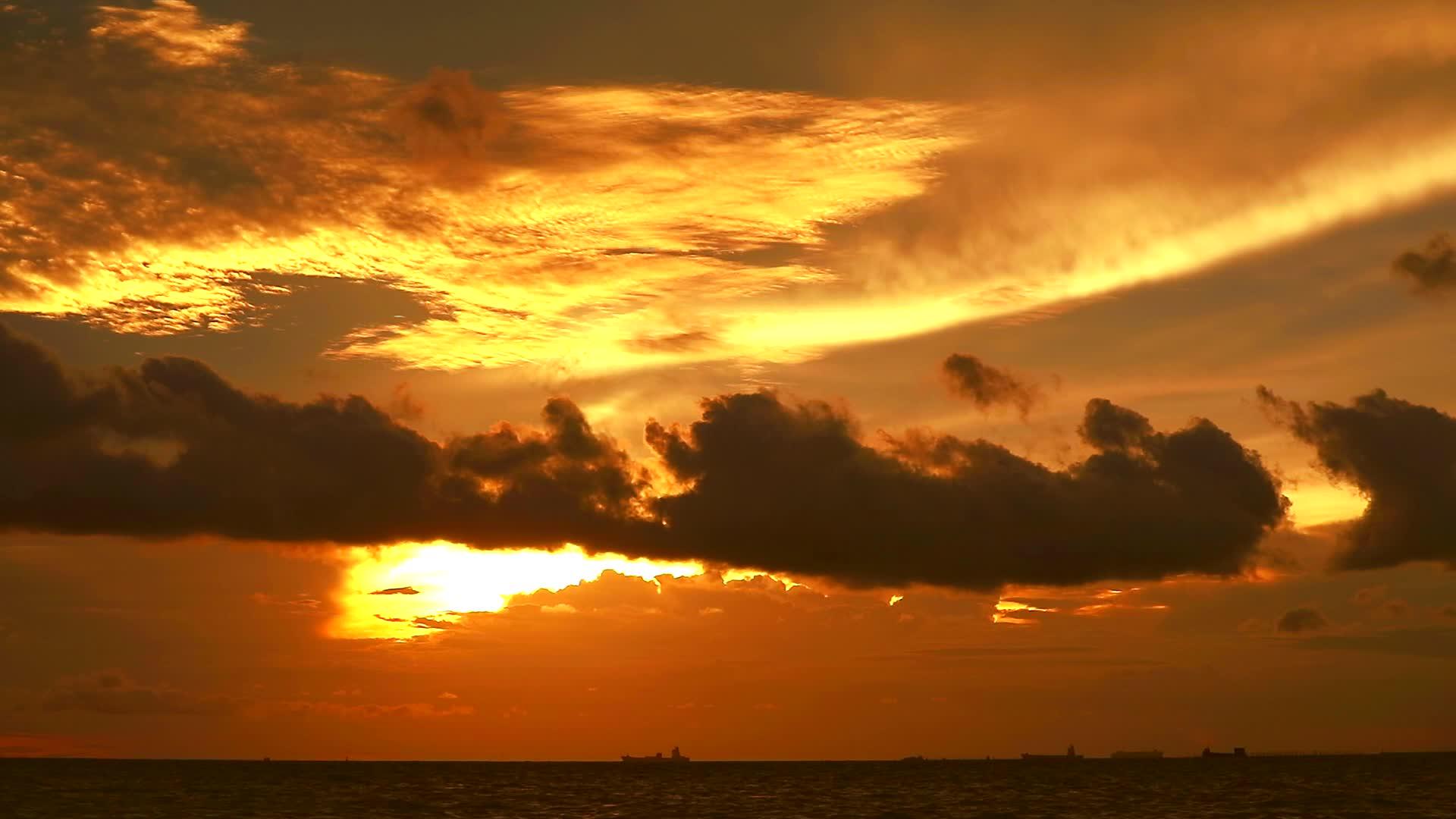 日落、橙黄色的天空和深红色的云在海上移动和停泊在船上视频的预览图