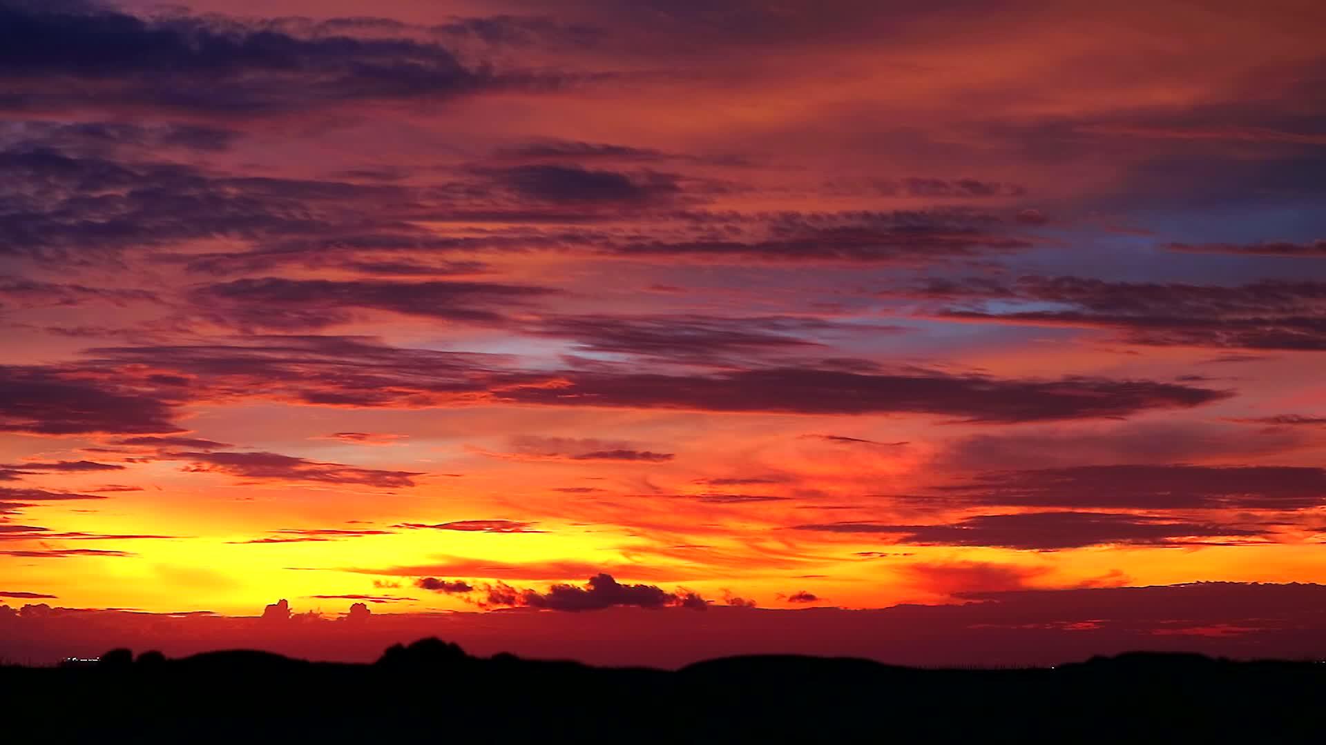 日落、橙色天空和深红色的云在模糊的双周山上飘动视频的预览图