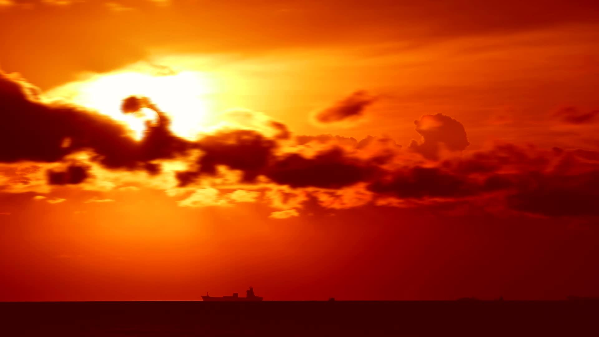 日落、橙红色的天空和暗红色的云在海上移动和停泊货船停泊在海上视频的预览图