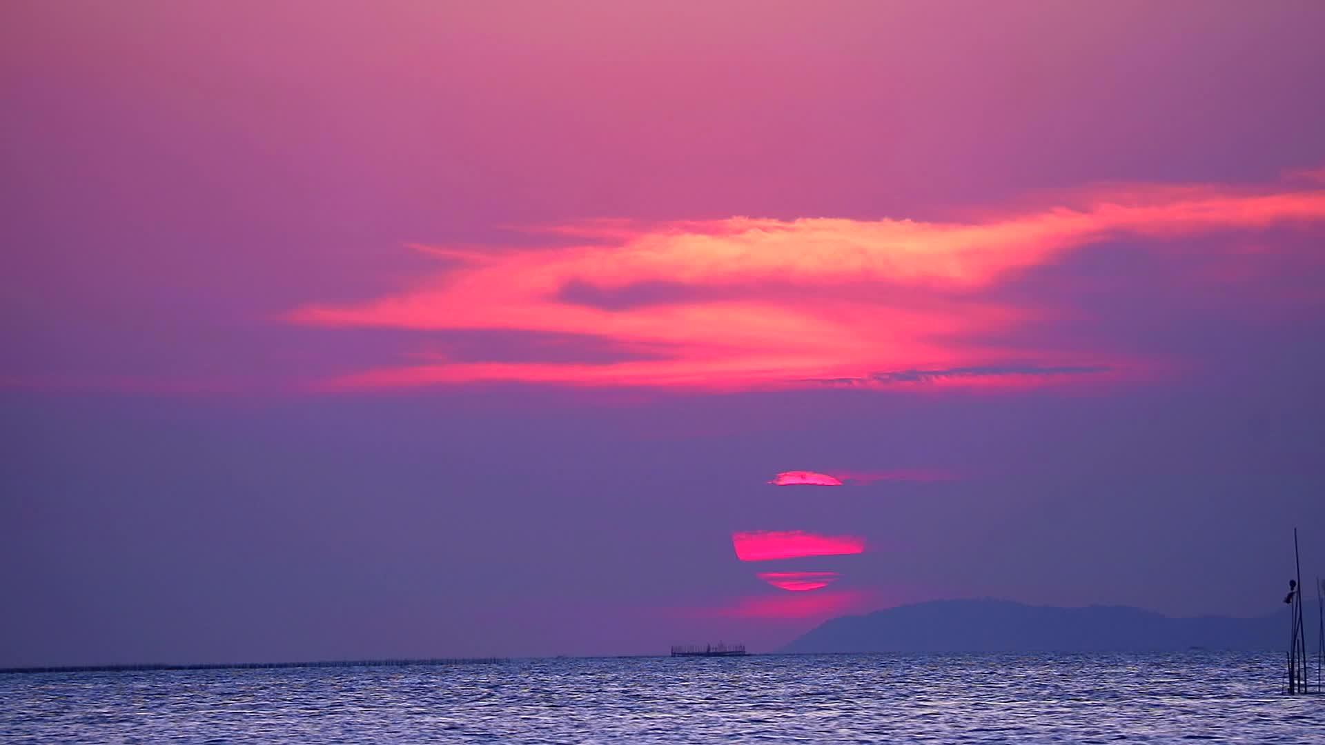 日落和紫色的云在天空中漂浮在海面上微小的波浪在移动视频的预览图