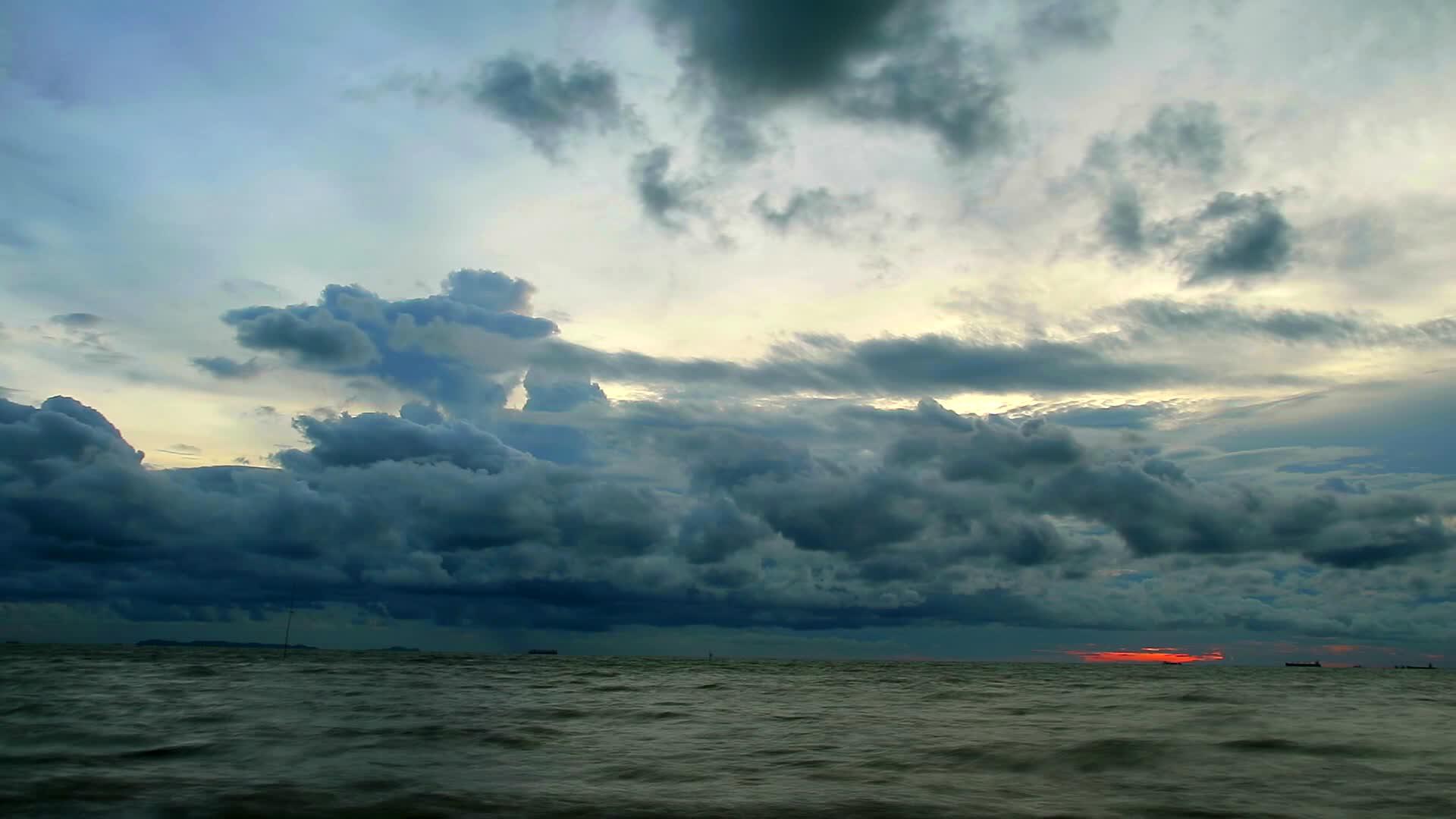 日落黑暗的天空雨云在雨水过期前漂浮在海面上视频的预览图