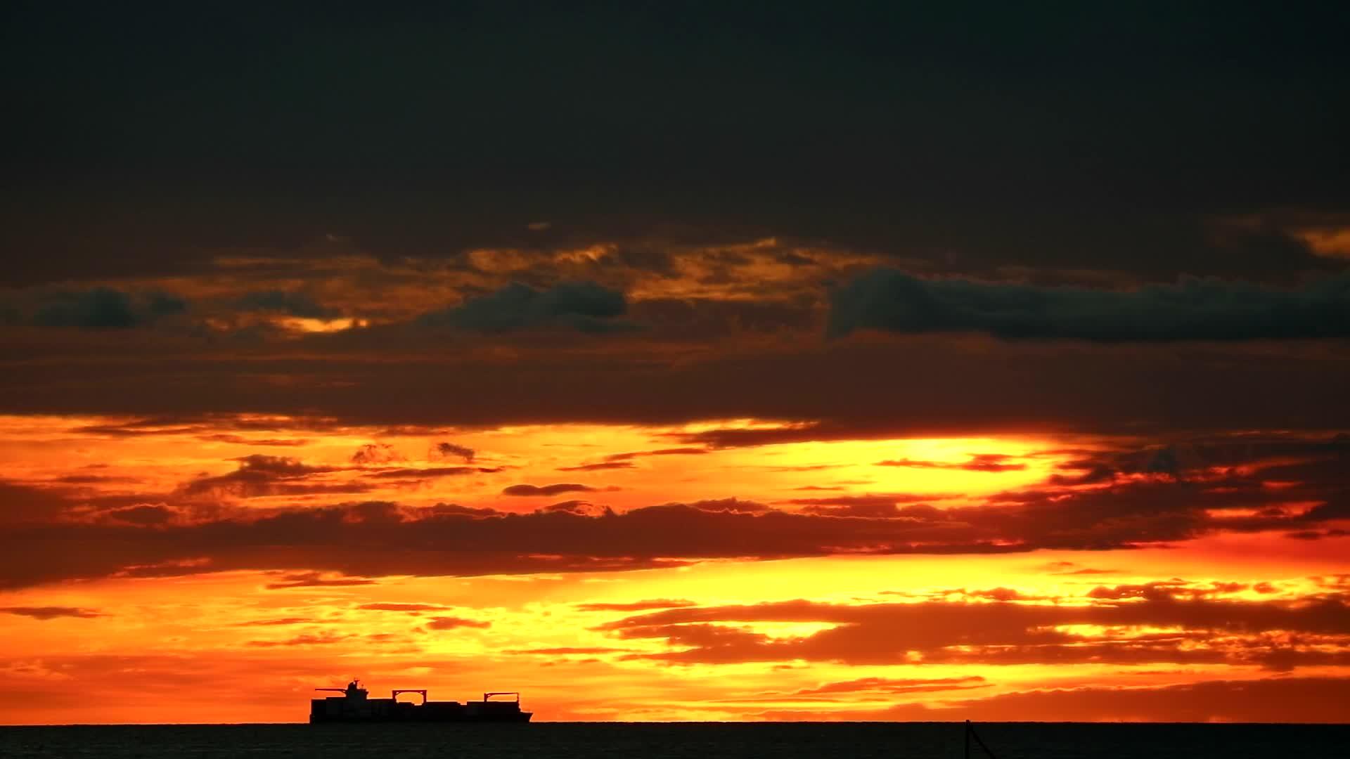 在海上航行的货船和在天空中日落的红橙山丘视频的预览图