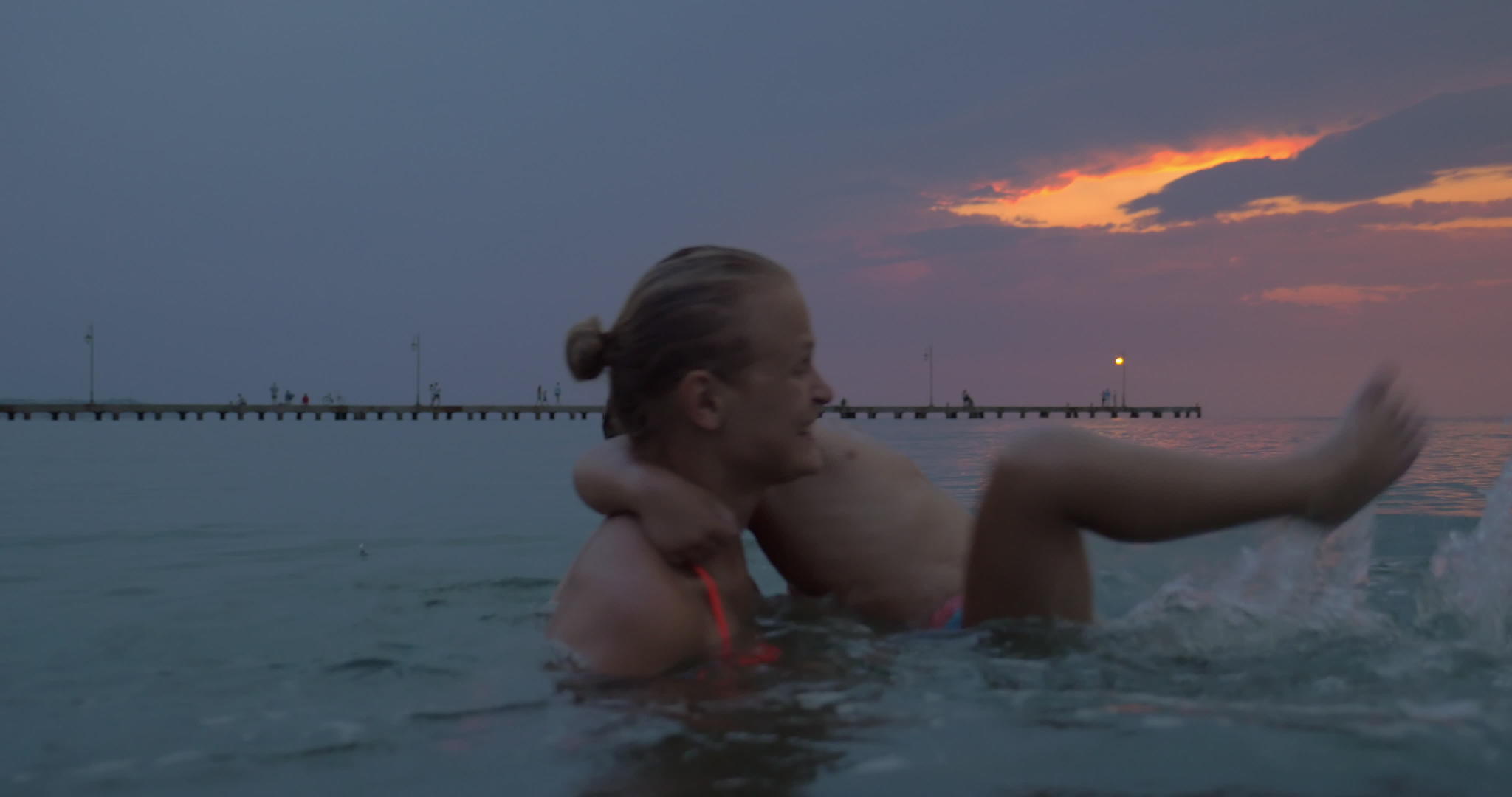 母亲和儿子在日落时在城市的海里游泳视频的预览图