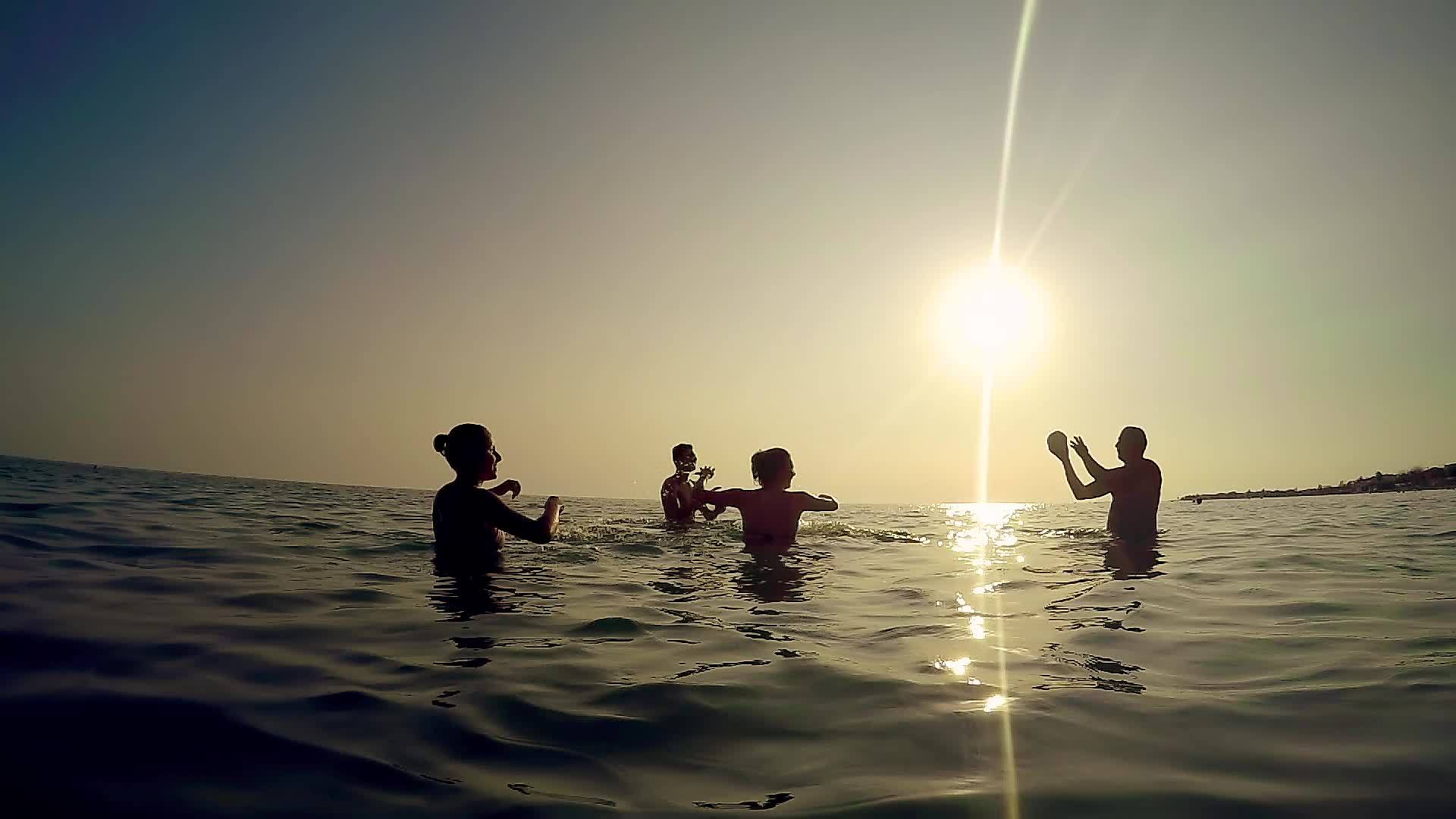 快乐的家庭在海洋中玩耍日落时溅水的剪影——热带游客视频的预览图
