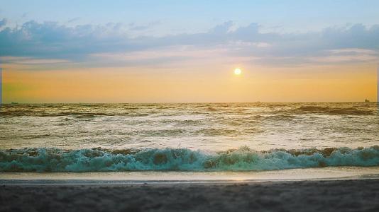 日落时太阳下山时海浪冲上沙滩视频的预览图