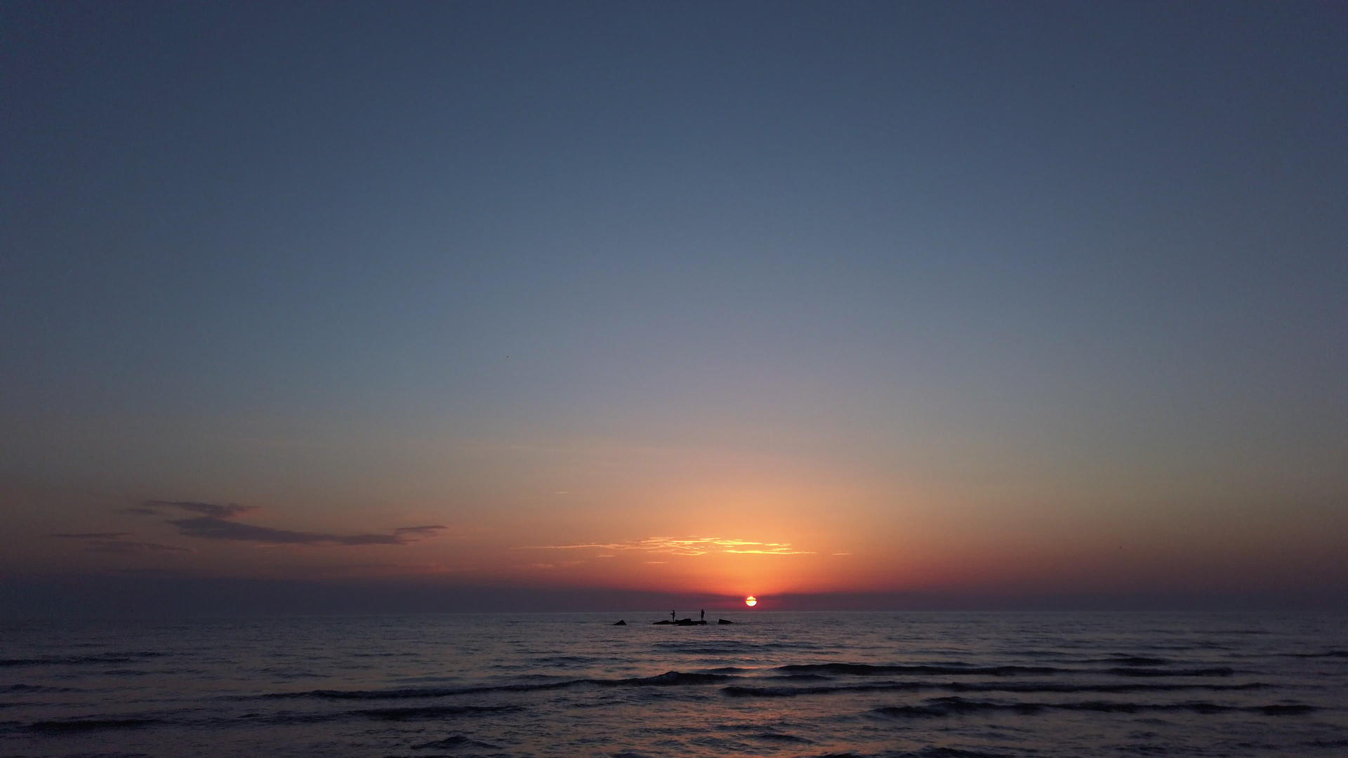 海滩上的日落海岩石上的浅影视频的预览图