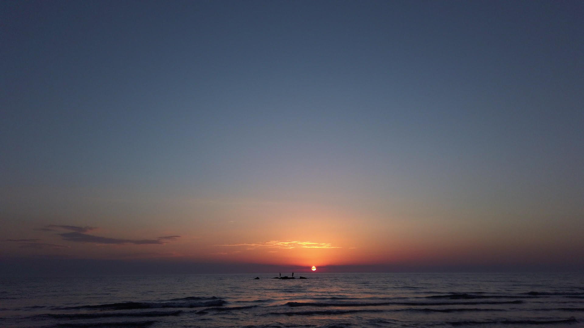 海滩上的日落海岩石上的浅影视频的预览图
