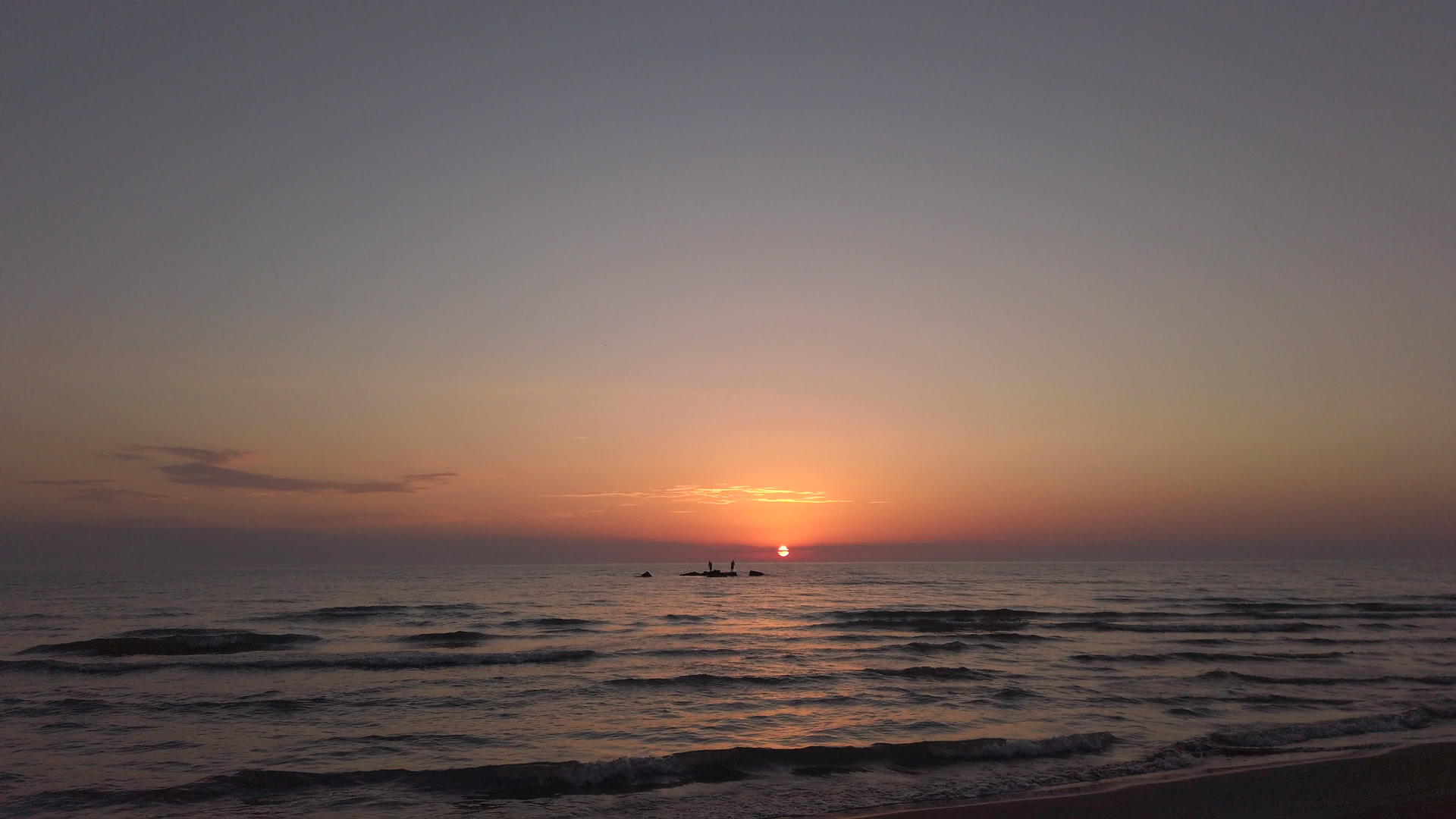 海滩上的日落海岩石上的浅影视频的预览图