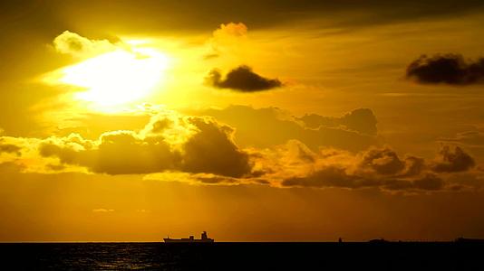 黄色的天空和深色的红云在海上移动停泊在船上的双月光下视频的预览图