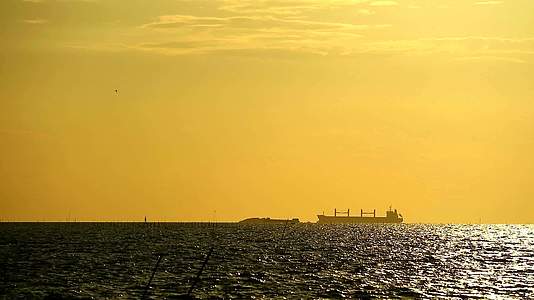 货船之后日落在黑色、橙色、黄色和金色的天空下视频的预览图