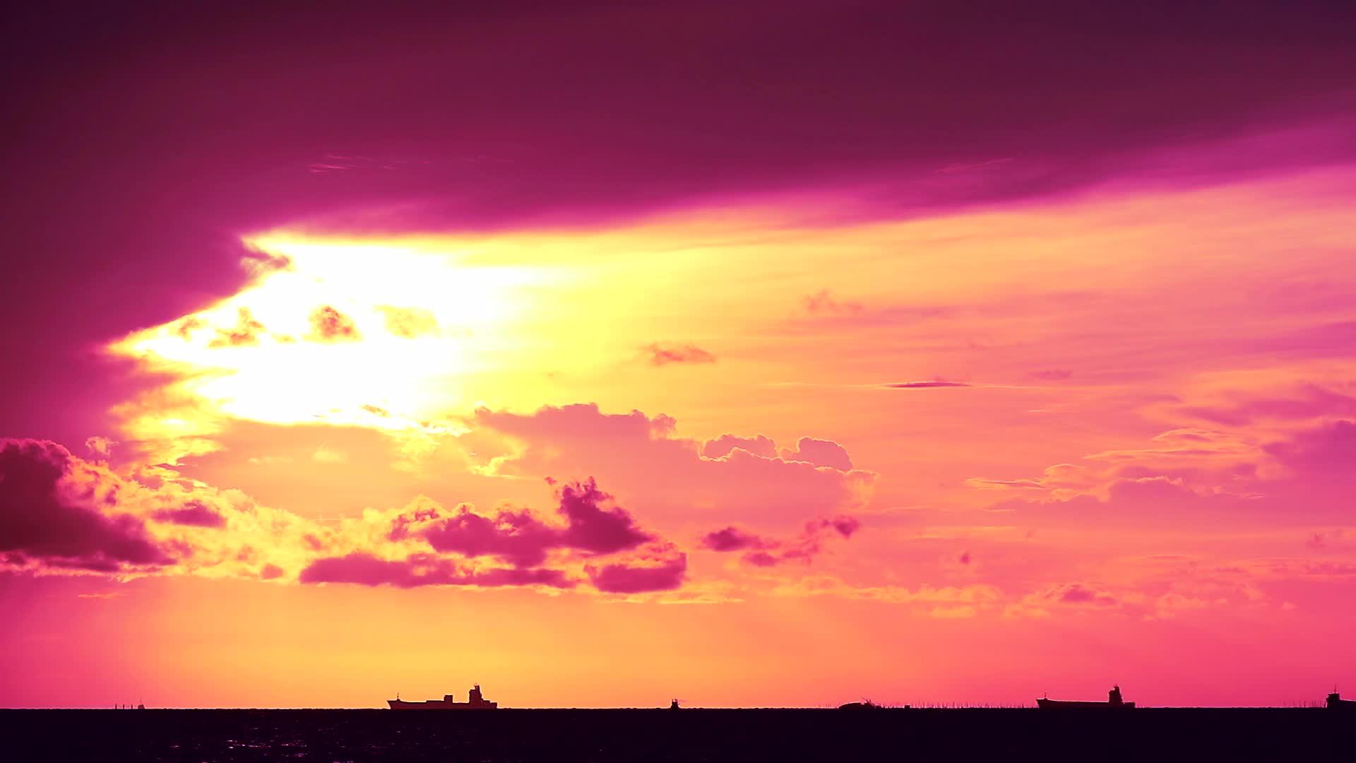 紫色的日落黄黄色的天空和深红色的云漂浮在海上和船只停泊处视频的预览图