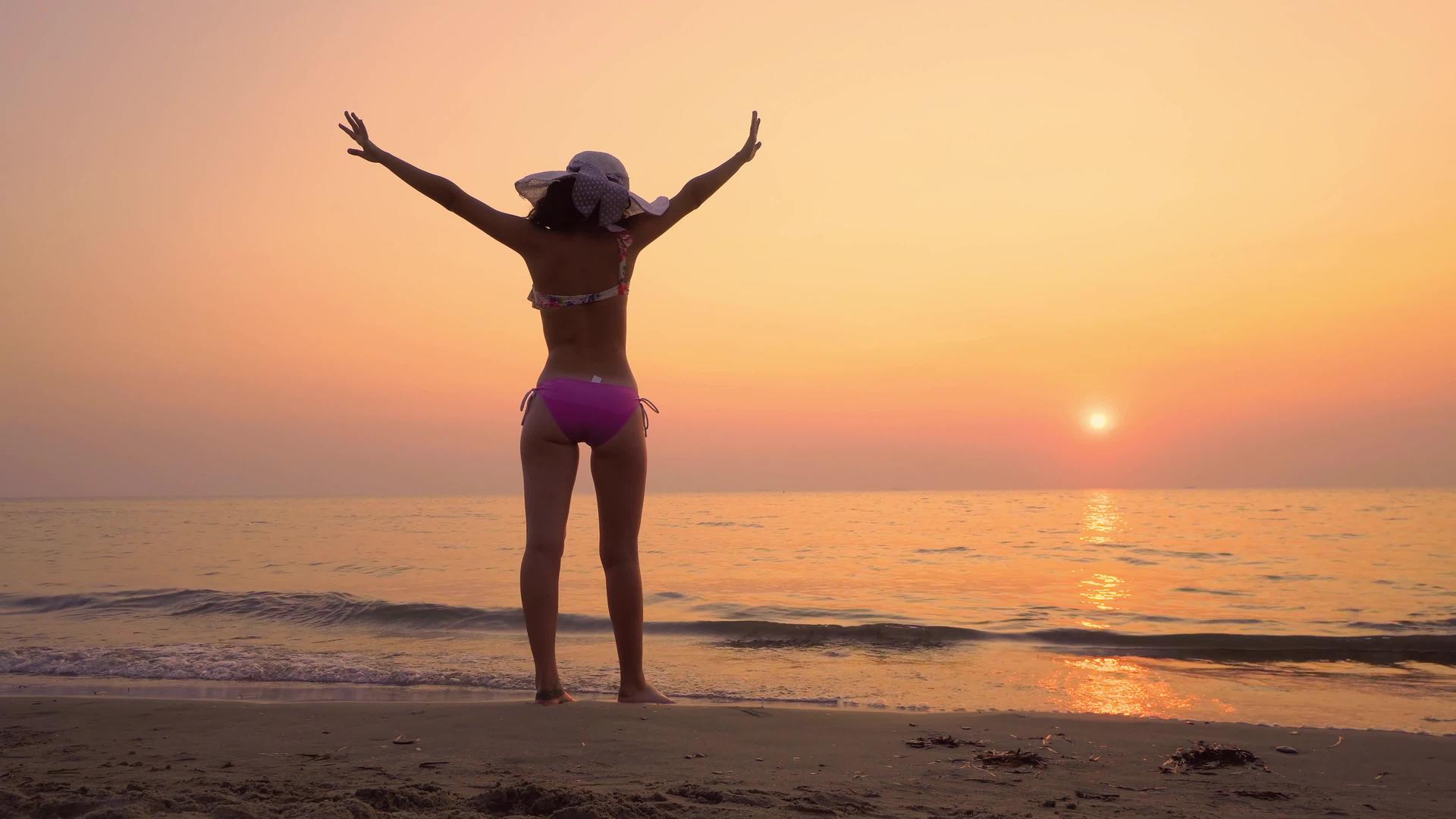 日出时自由快乐的女人举手看着幕后的太阳视频的预览图