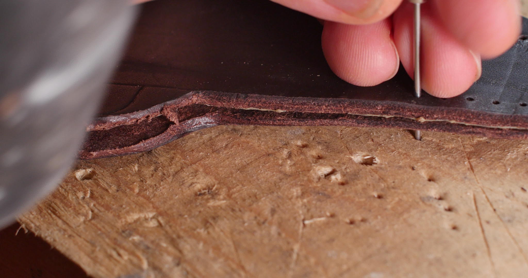 男人用手在一块生皮革上打孔做出时尚的手工皮革工艺视频的预览图