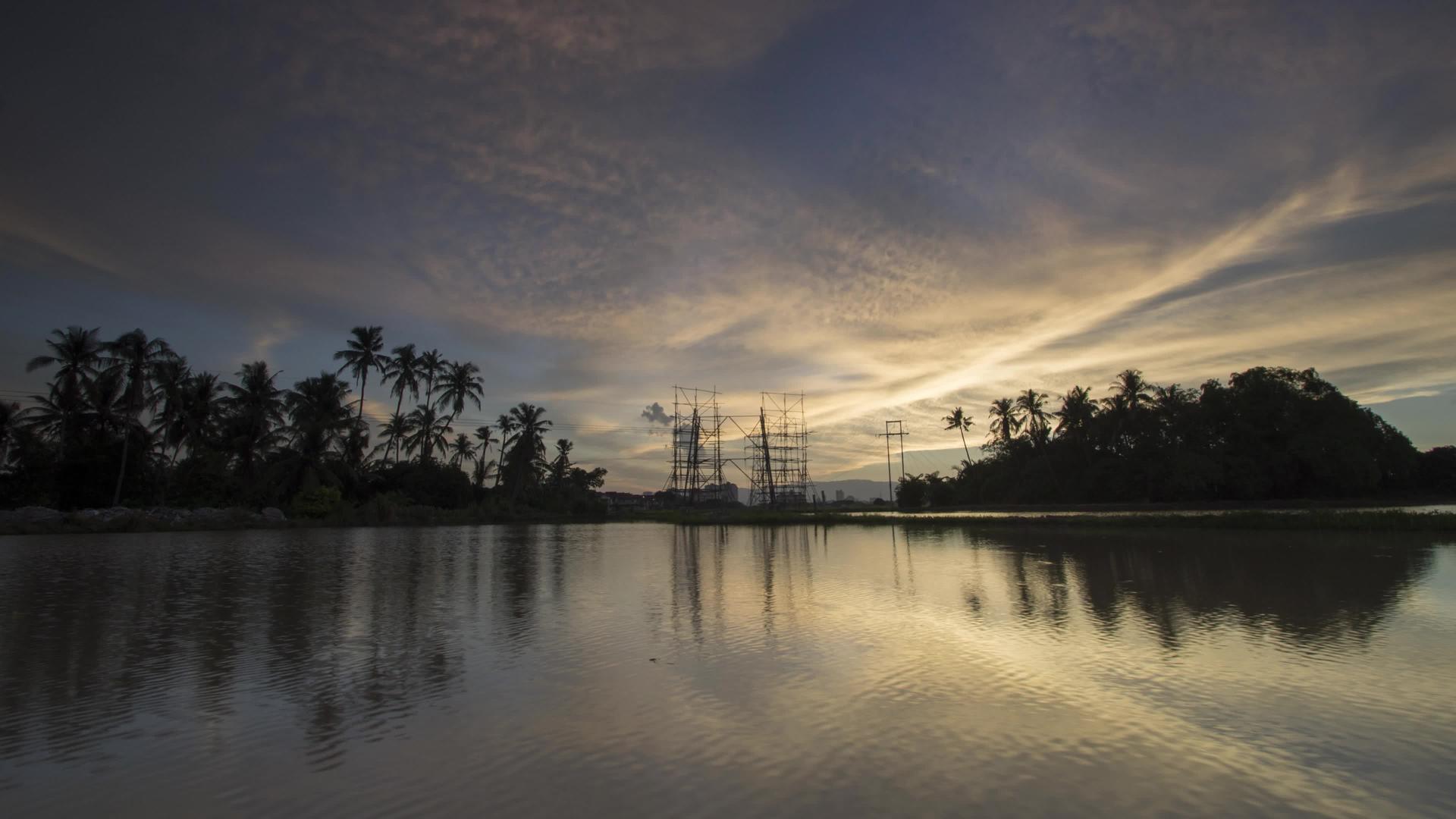 日落时间的建筑高压塔和椰子树视频的预览图