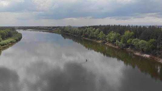 在下游宽阔而平静的河流木筏的河床上一艘皮艇上的人类视频的预览图