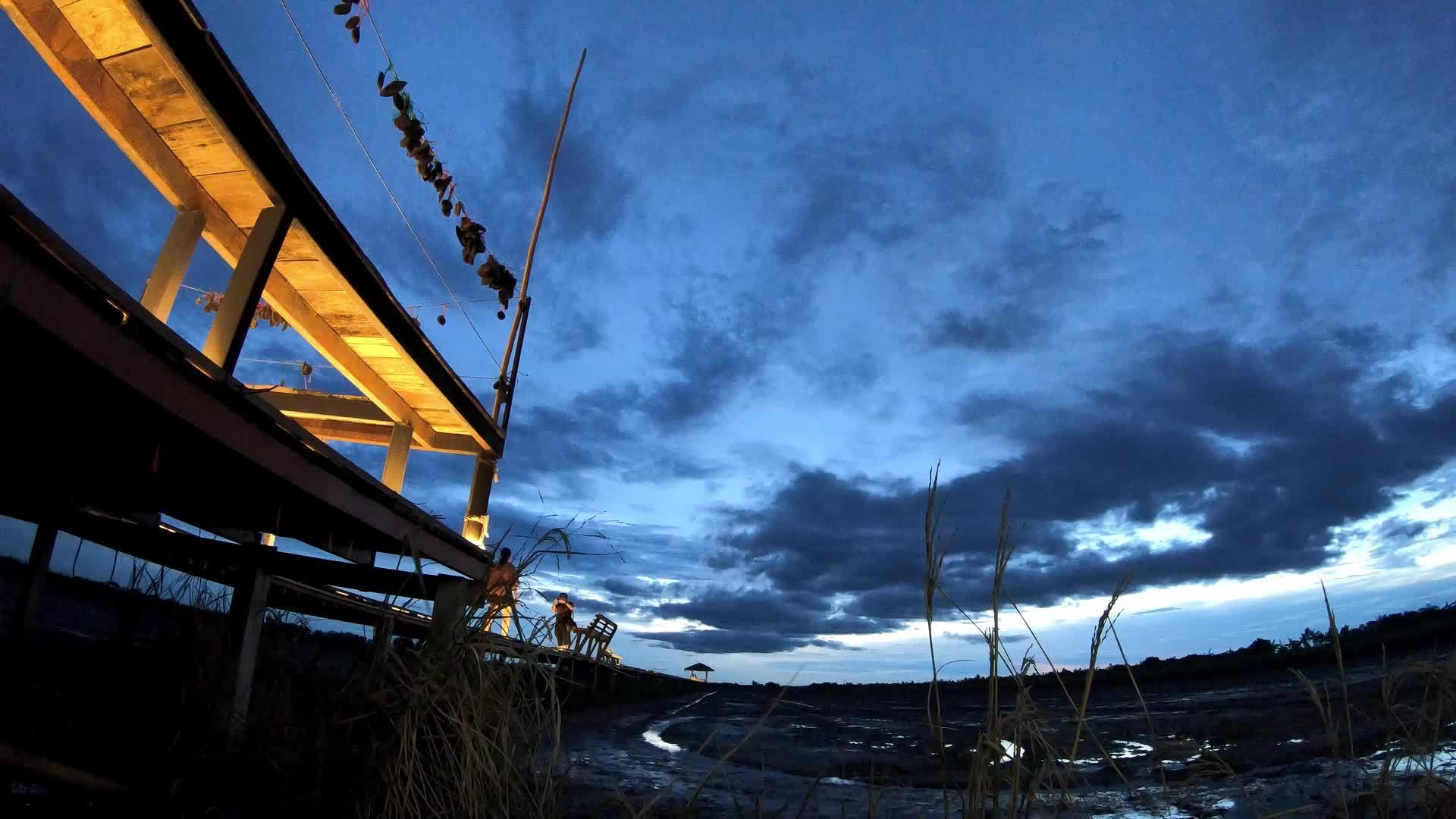 木桥上模糊的观光者和夜间太阳的反射云视频的预览图