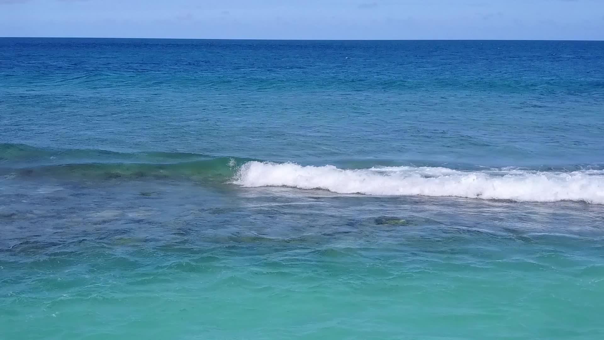 关闭休闲度假胜地通过蓝海和冲浪附近的清洁海滩背景视频的预览图