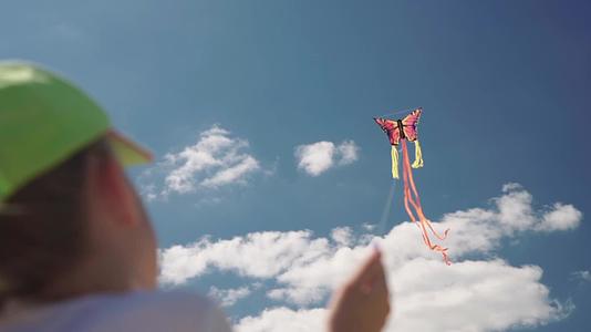 在阳光明媚的日子里戴着帽子的女孩玩风筝的慢动作是完美的视频的预览图