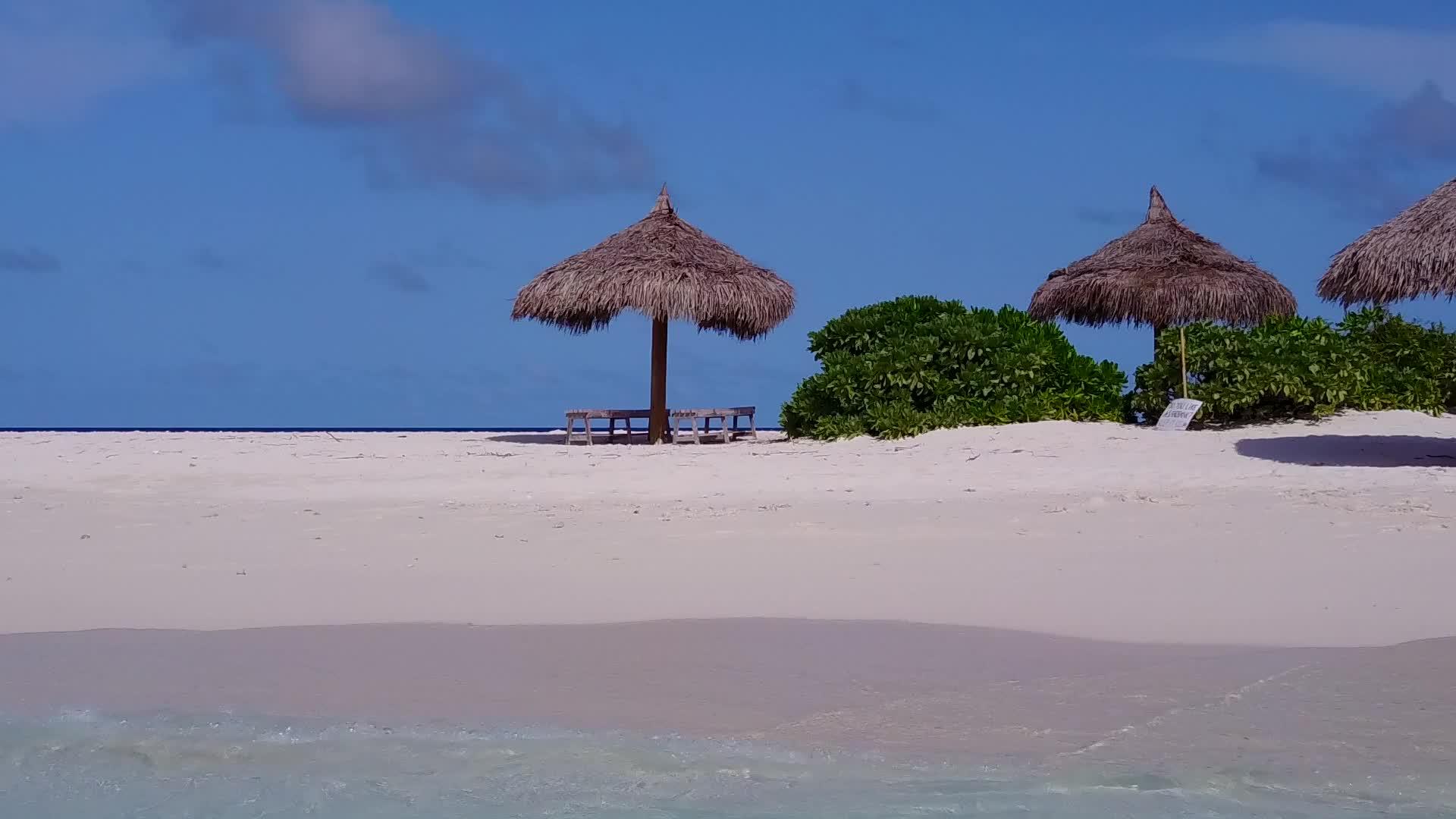 以透明海面和海滩附近的白沙土为背景白天全景热带环礁视频的预览图