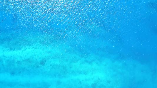 在阳光下欣赏以白沙为背景的蓝色海洋近距离欣赏豪华海岸海滩视频的预览图