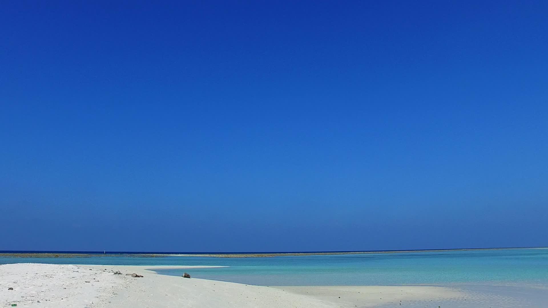在阳光下的浅沙背景下被清澈的蓝色水分隔开的水蓝色水层打破了环礁湖视频的预览图