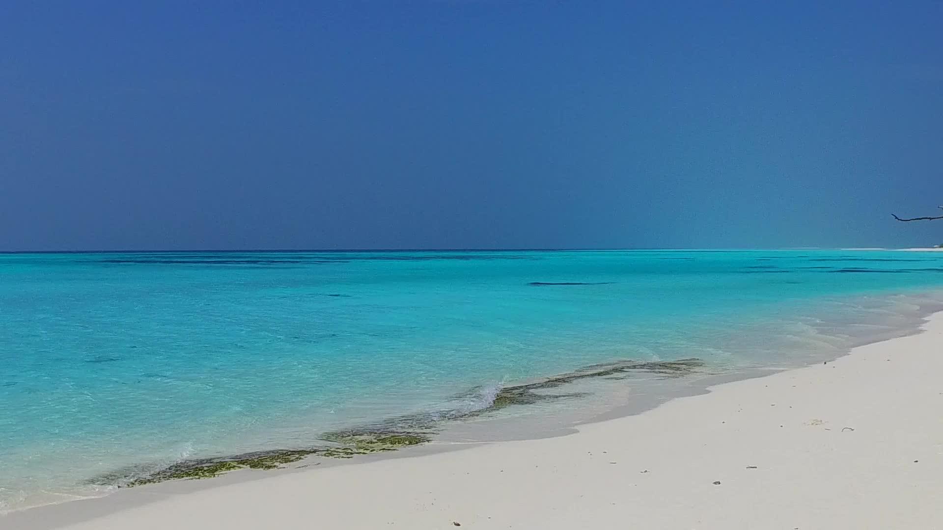海滩附近的蓝色水域和白色沙滩上的白色沙滩落在阳光明媚的海滩度假胜地视频的预览图