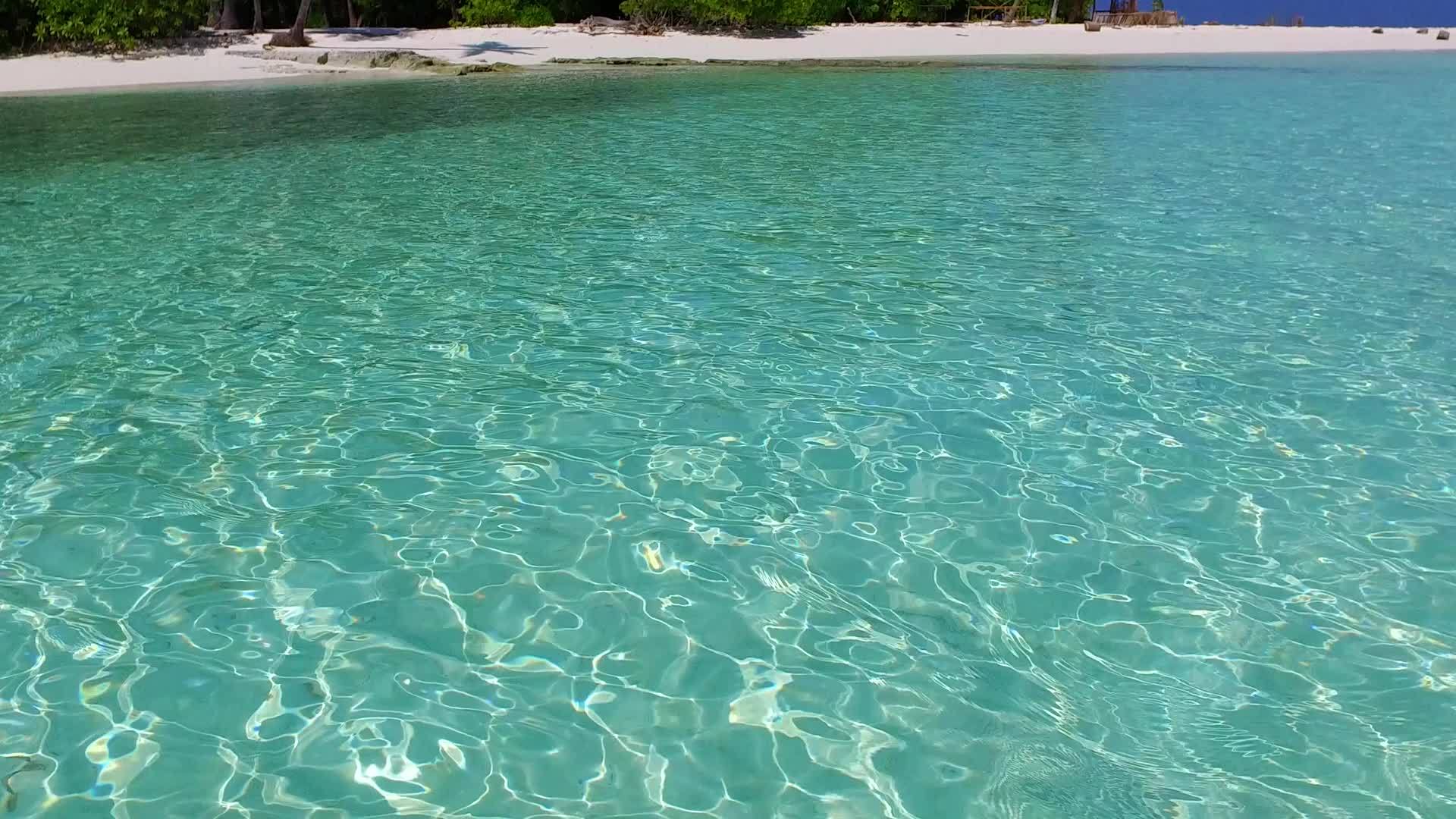 以蓝色环礁湖和白色沙滩为背景在阳光明媚的海浪附近航行视频的预览图