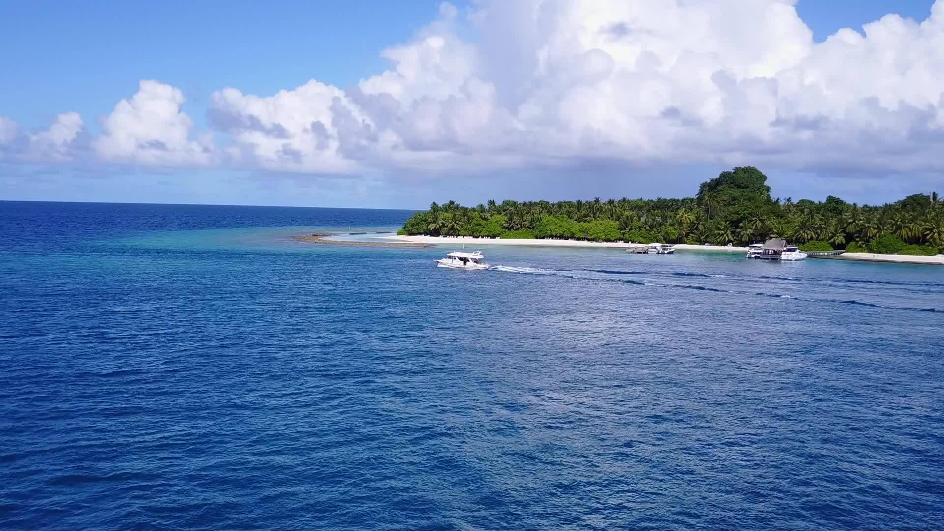 海滨海滩沿着蓝色海洋航行棕榈树附近有一个白色的沙底背景视频的预览图