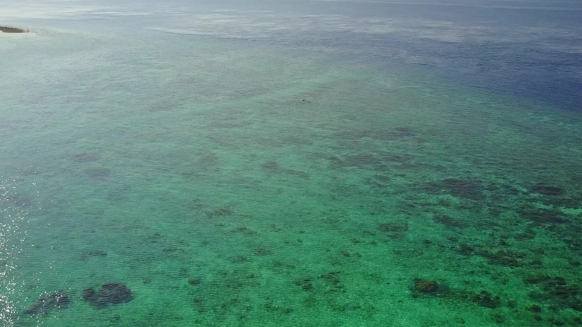 度假胜地附近有白色沙底背景的蓝色环礁湖视频的预览图