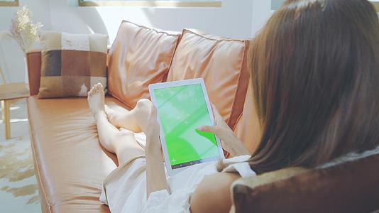 4K女性沙发上划平板电脑绿幕素材视频的预览图
