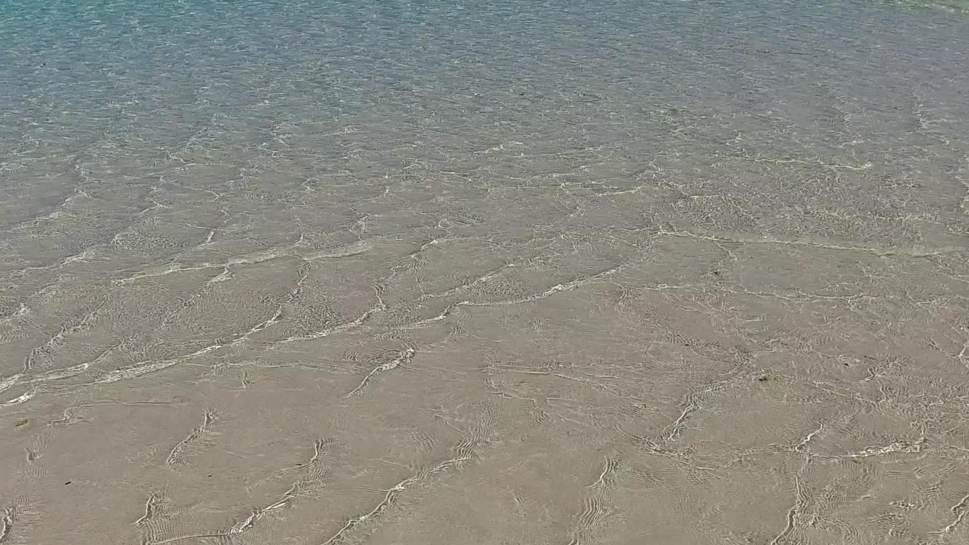 浅环礁湖在冲浪附近有明亮的沙背景沿着浅浅的泻湖视频的预览图