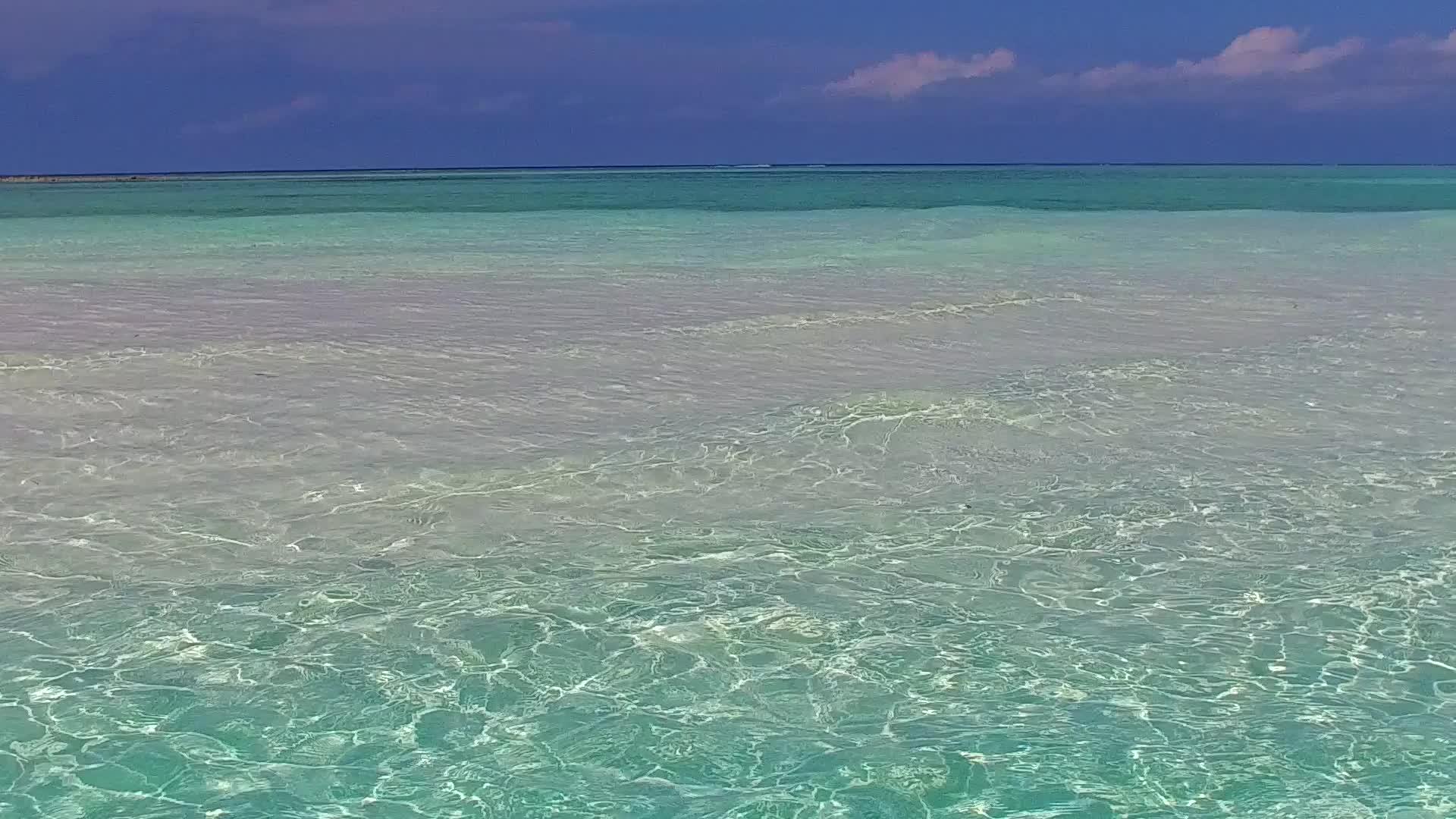 热带环礁湖海滩沿着蓝色海洋旅行的宽角景观白沙背景接近波浪视频的预览图
