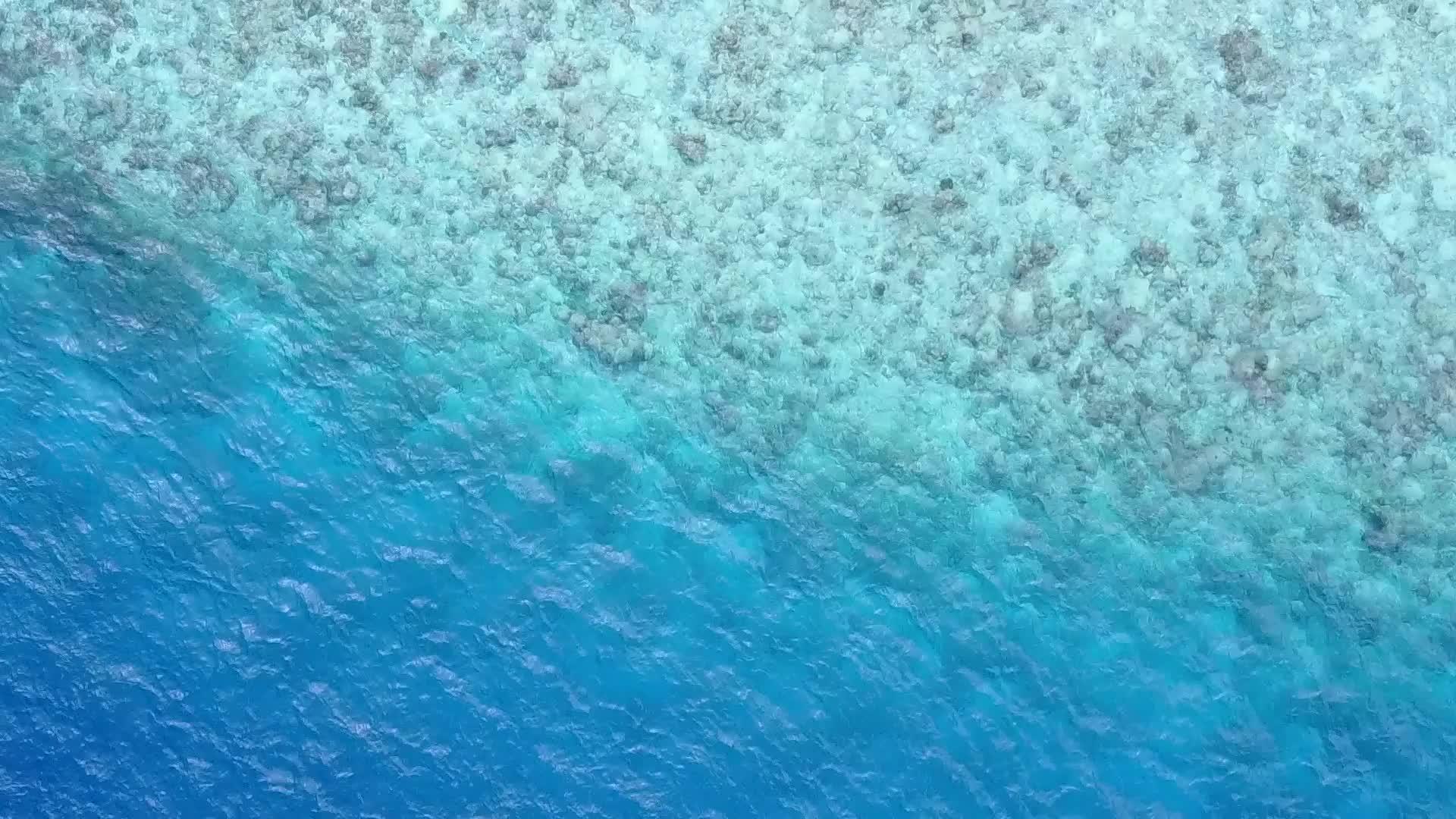 蓝色的水和接近冲浪的白色沙滩背景的蓝色水被完美地描绘出来视频的预览图