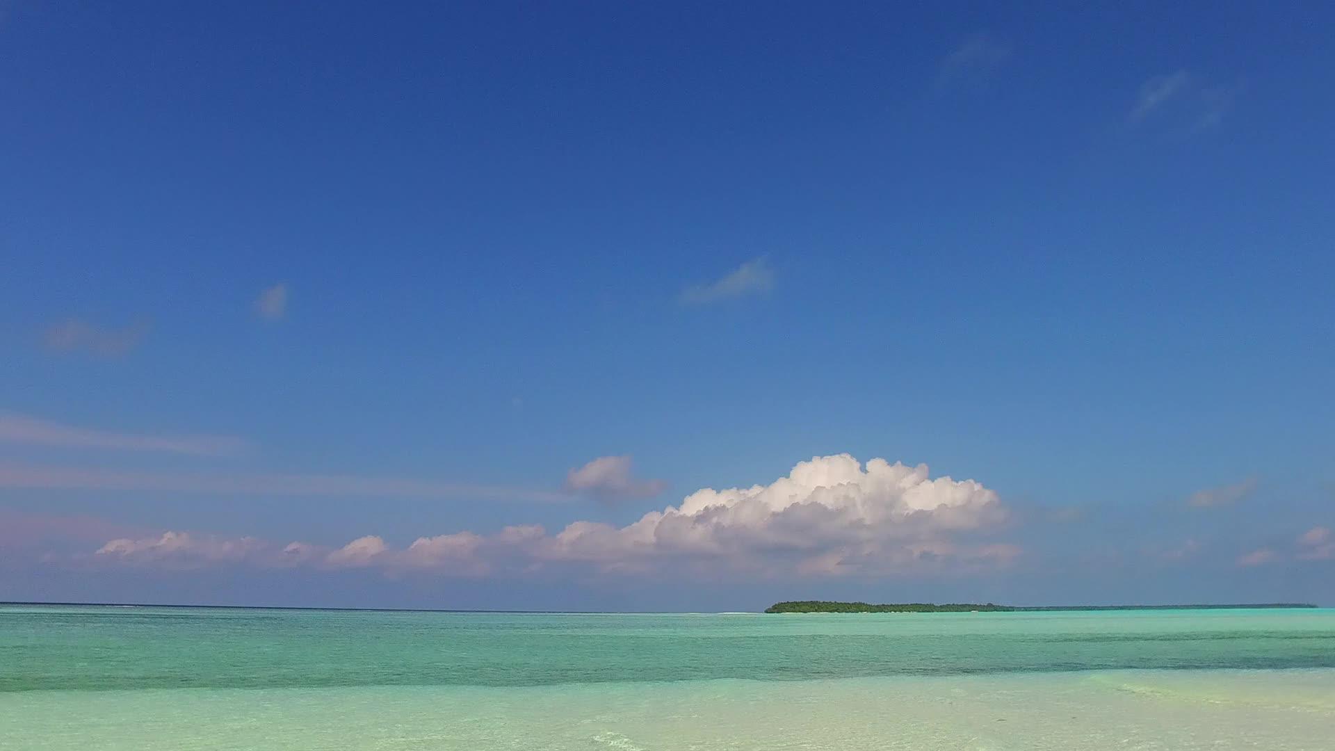 海滩附近透明的海洋和白色的沙底背景阳光明媚的环礁视频的预览图