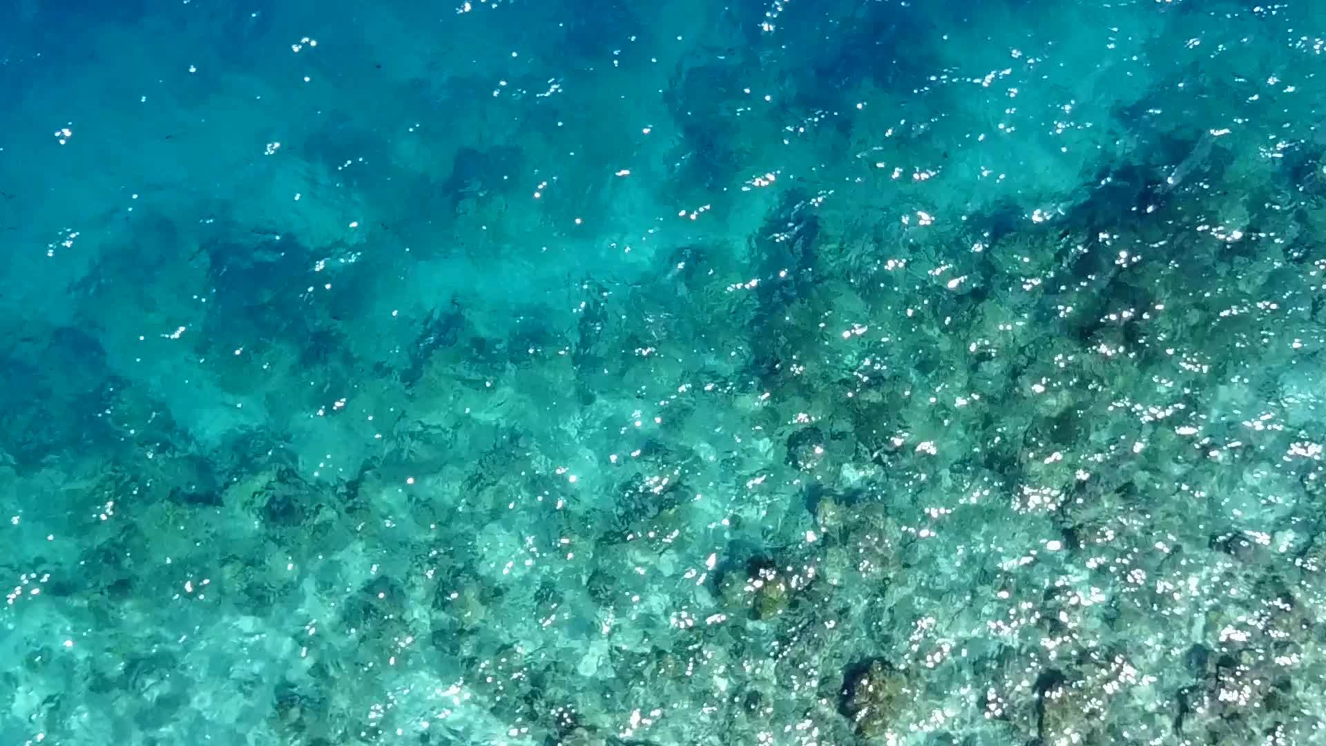 在蓝色的环礁湖上航行阳光明媚海浪附近有白色的海滩视频的预览图