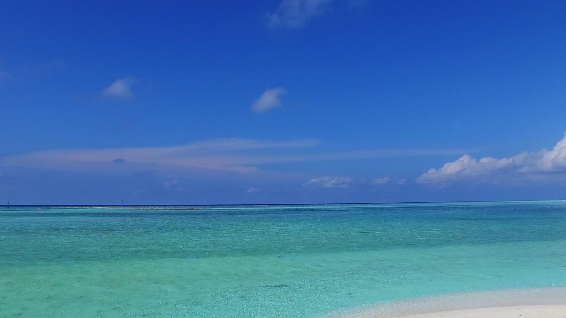蓝绿色的海洋沿着蓝绿色的海洋和白色的沙底背景在度假胜地附近平静视频的预览图