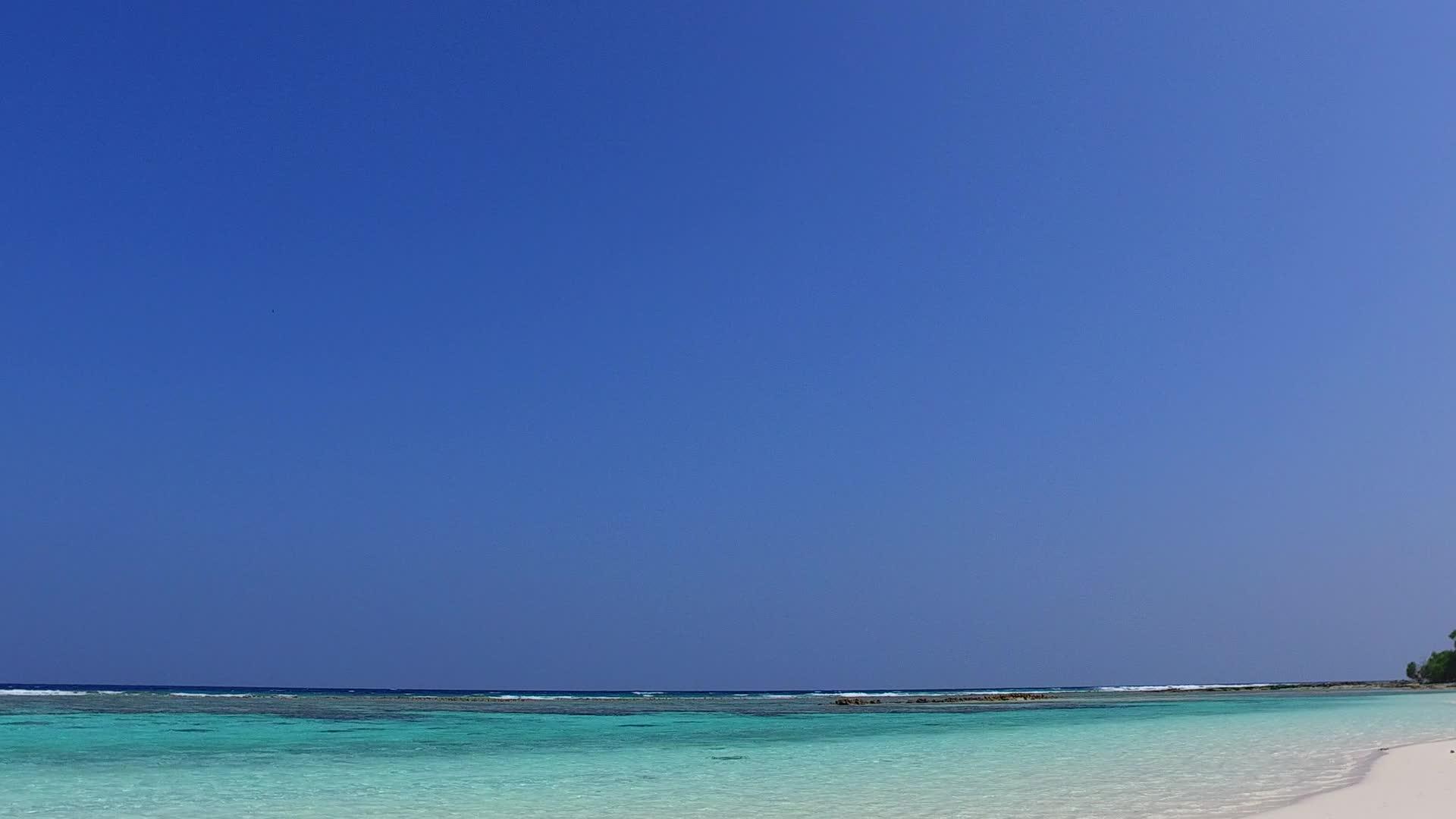 蓝色泻湖热带度假海滩特写镜头靠近棕榈树的白色沙滩背景视频的预览图