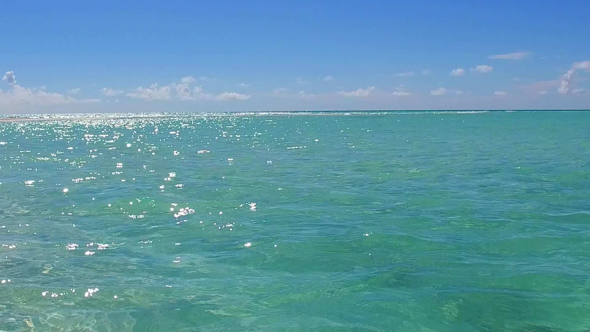 在沙洲附近的蓝海和白沙的背景下阳光明媚的度假海滩阳光明媚视频的预览图