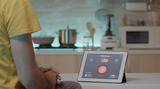 男人用智能软件在厨房桌子上看平板电脑视频的预览图