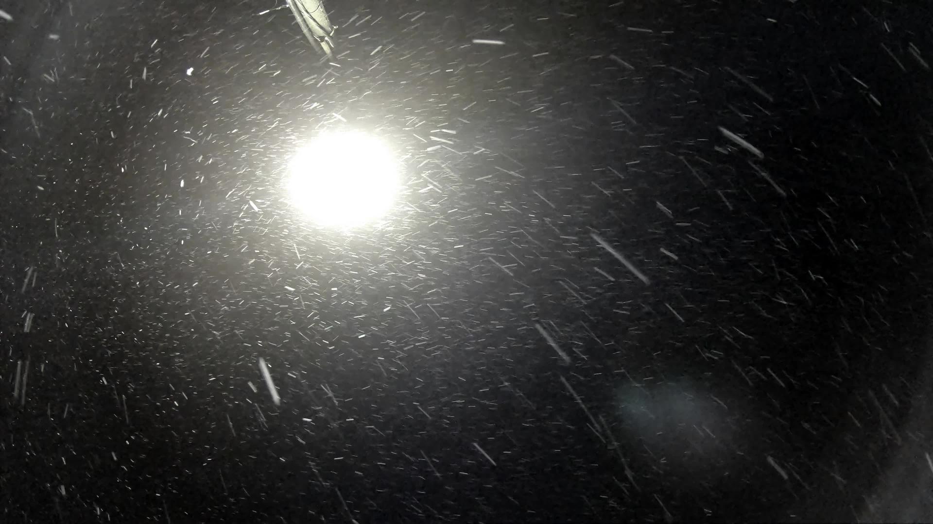 寒冷的雪和雪在夜间冬季暴风雪中缓慢飘动视频的预览图
