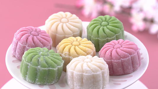 彩色雪皮月饼甜雪月饼中秋节传统咸甜点淡粉色背景特写视频的预览图