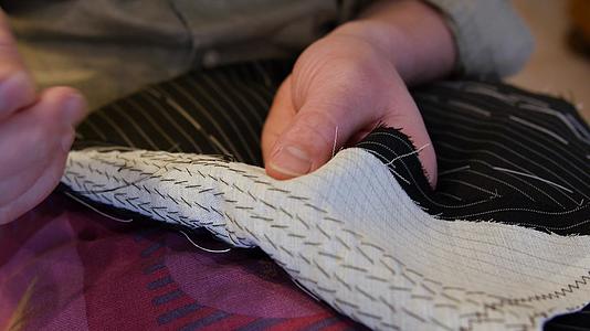 英俊的男士裁缝手垫缝西装翻领将两层或两层以上的织物固定视频的预览图
