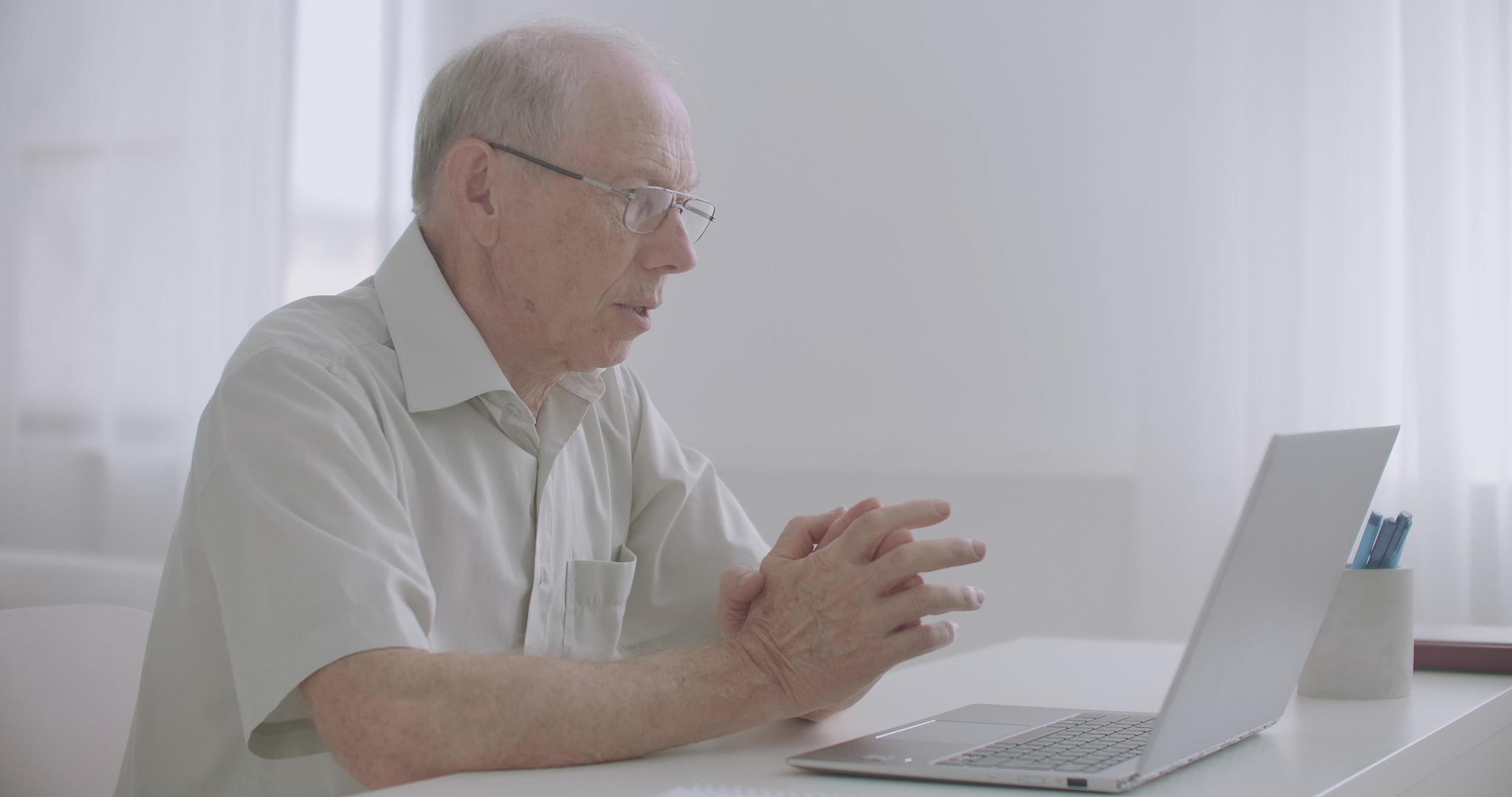 经验丰富的老年男性专家通过笔记本电脑与同事一起工作视频的预览图