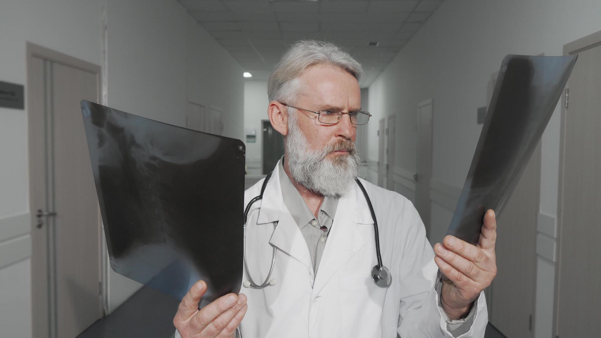 高级男医生在镜头上微笑着比较了两张x光扫描视频的预览图