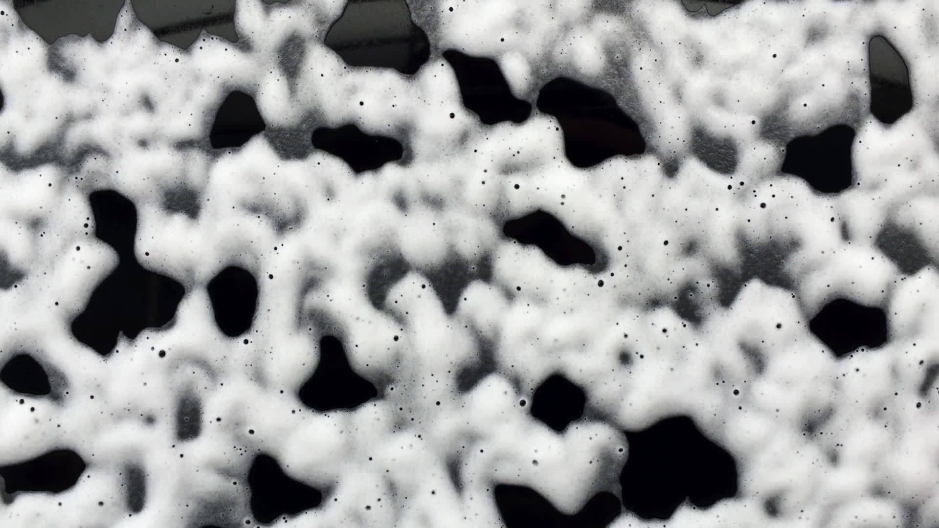 抽象的白色泡沫泡沫滑下黑色玻璃洗车香波清洗视频的预览图