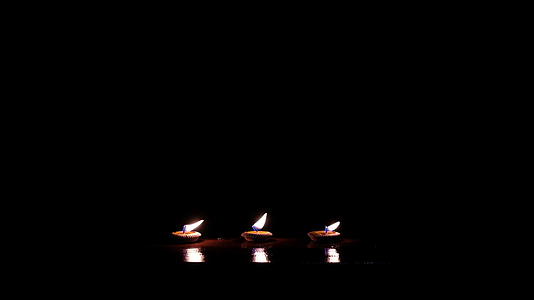 小托盘上的三根芳香蜡烛在黑暗中发光视频的预览图