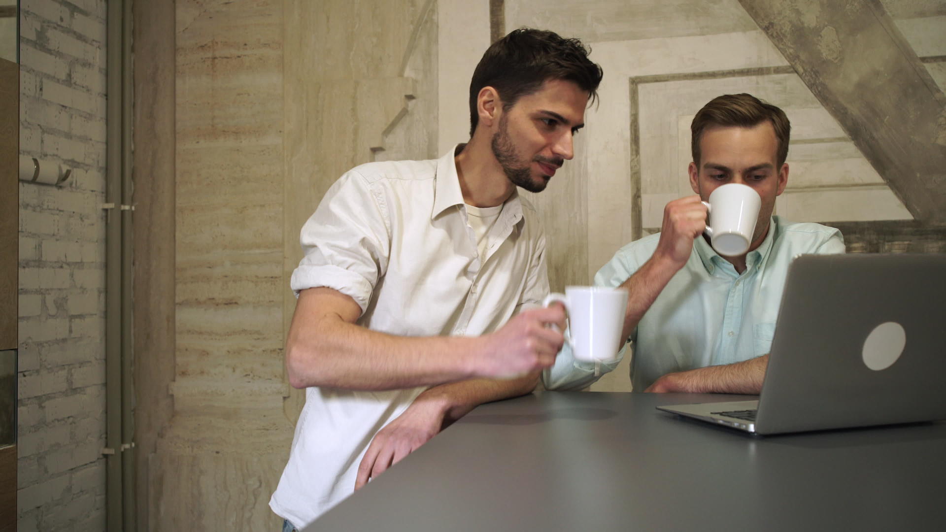 两个年轻的职业男人喝咖啡找电脑聊天视频的预览图