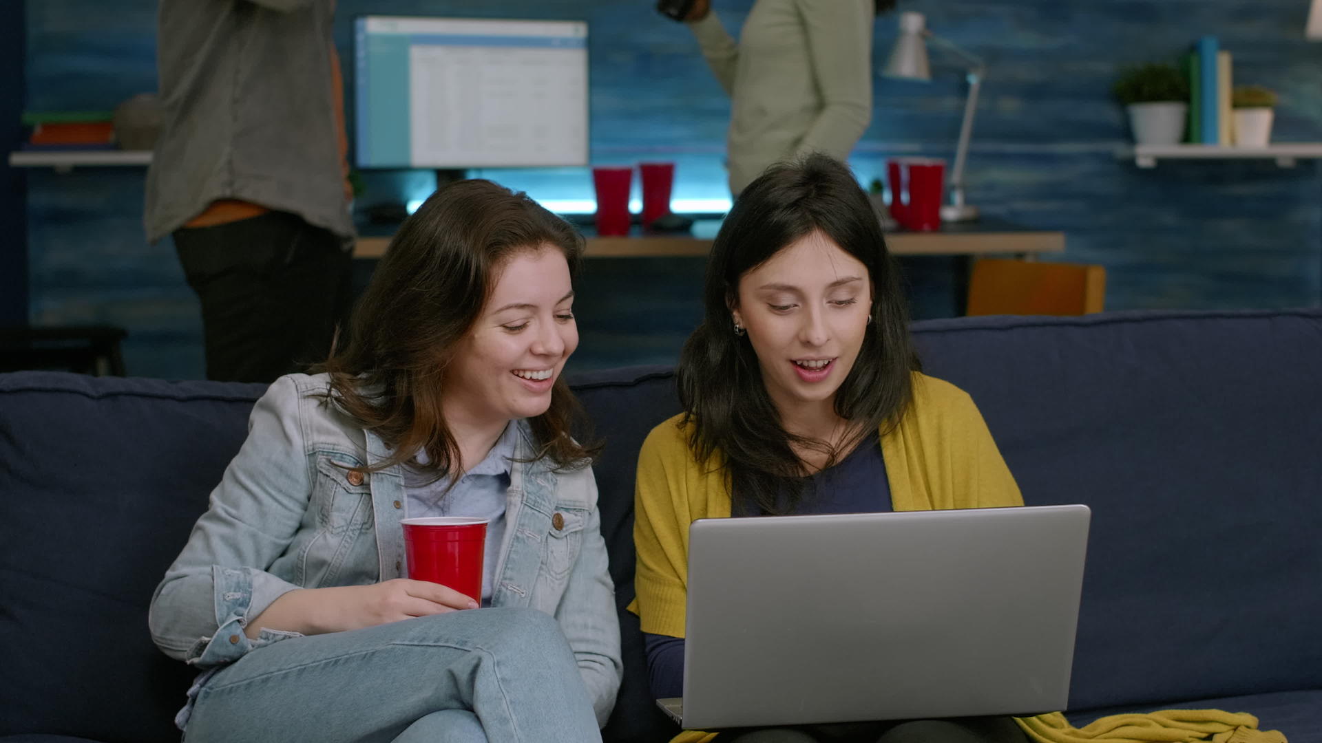 两个女人坐在沙发上看笔记本电脑喜剧系列视频的预览图