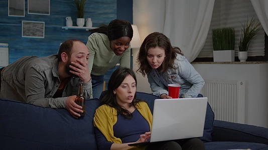 多民族朋友在电脑上看有趣的喜剧电影用笔记本电脑视频的预览图